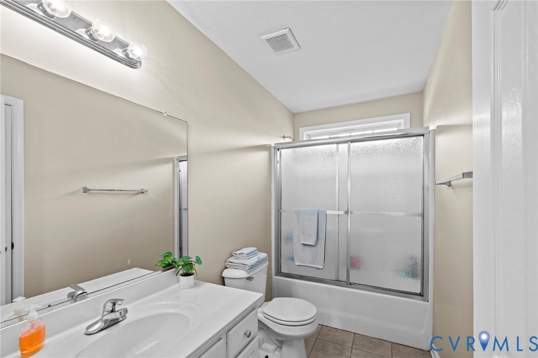 Bathroom featuring a white vanity with integrated sink, chrome faucet, and a large wall-mounted mirror