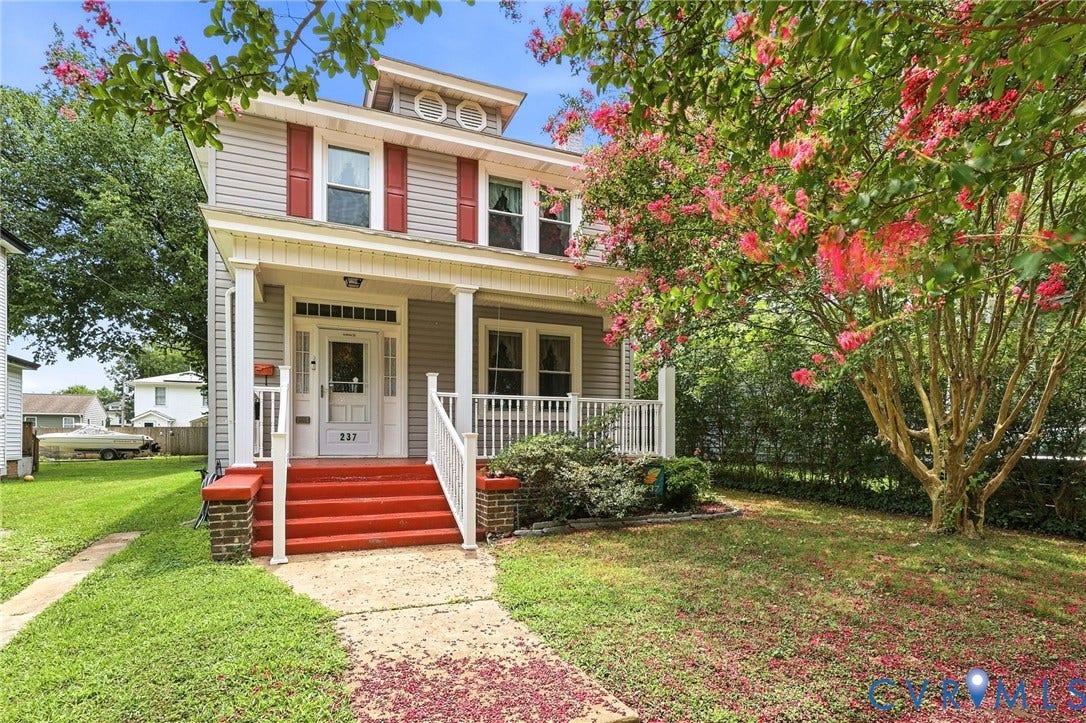 Two-story home featuring light gray siding with red window shutters and a white trim