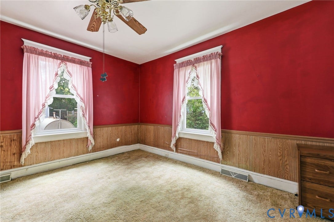 Room featuring two windows, wood-finish wall paneling, and a ceiling fan with integrated lighting