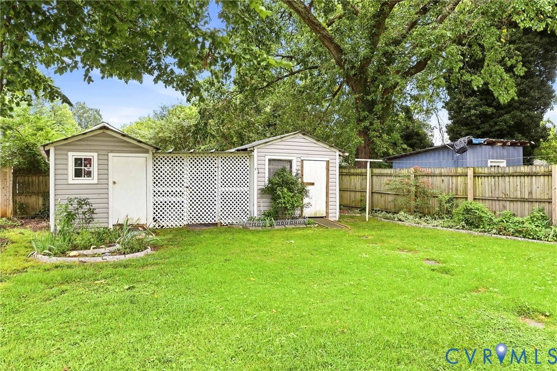 Expansive backyard featuring two storage sheds, a lattice privacy screen, and a wood privacy fence