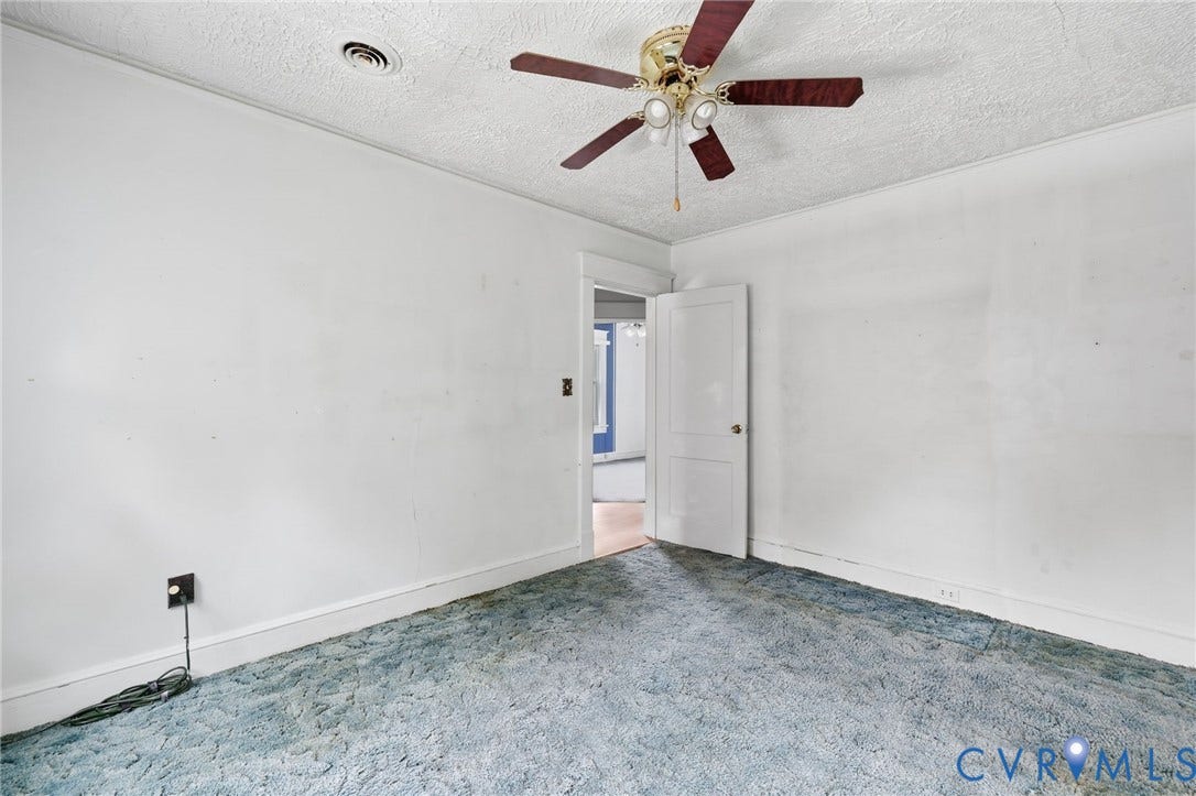 Room featuring a ceiling fan with light fixture, textured ceiling, and an interior door