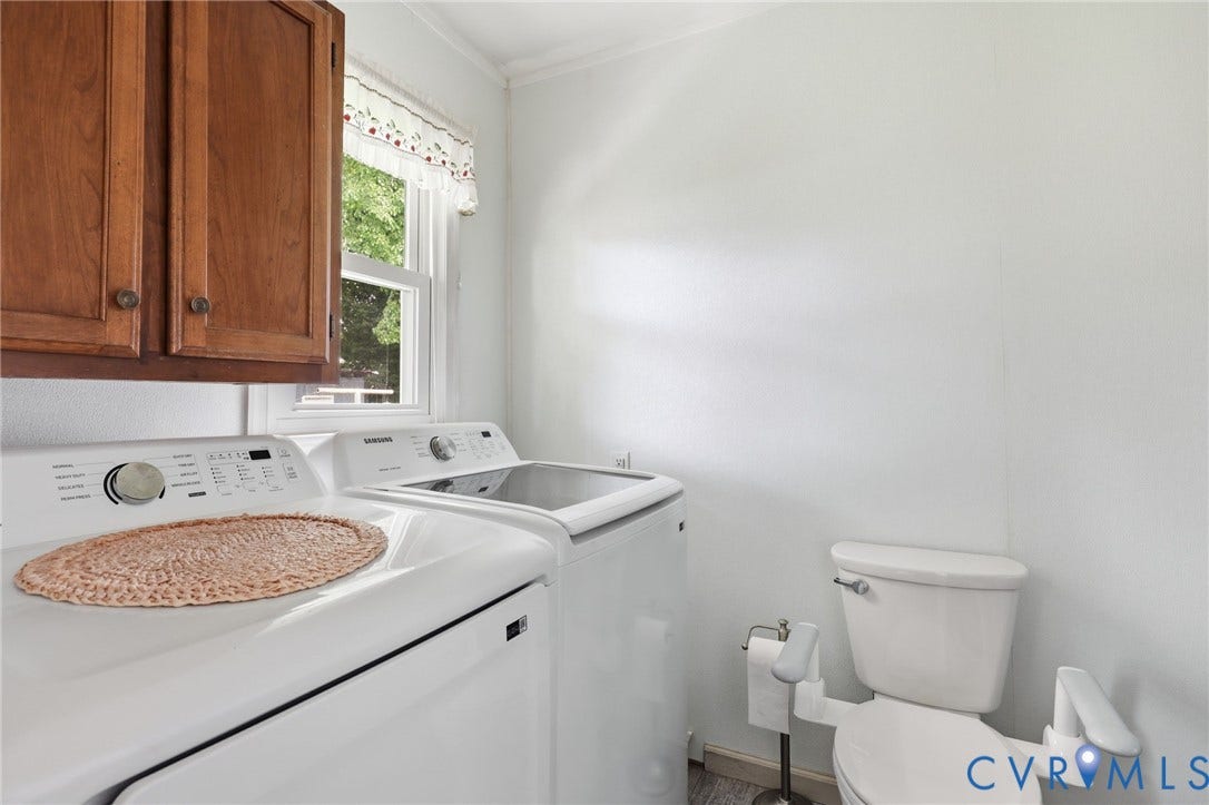Dedicated laundry area featuring overhead wood cabinetry and a window