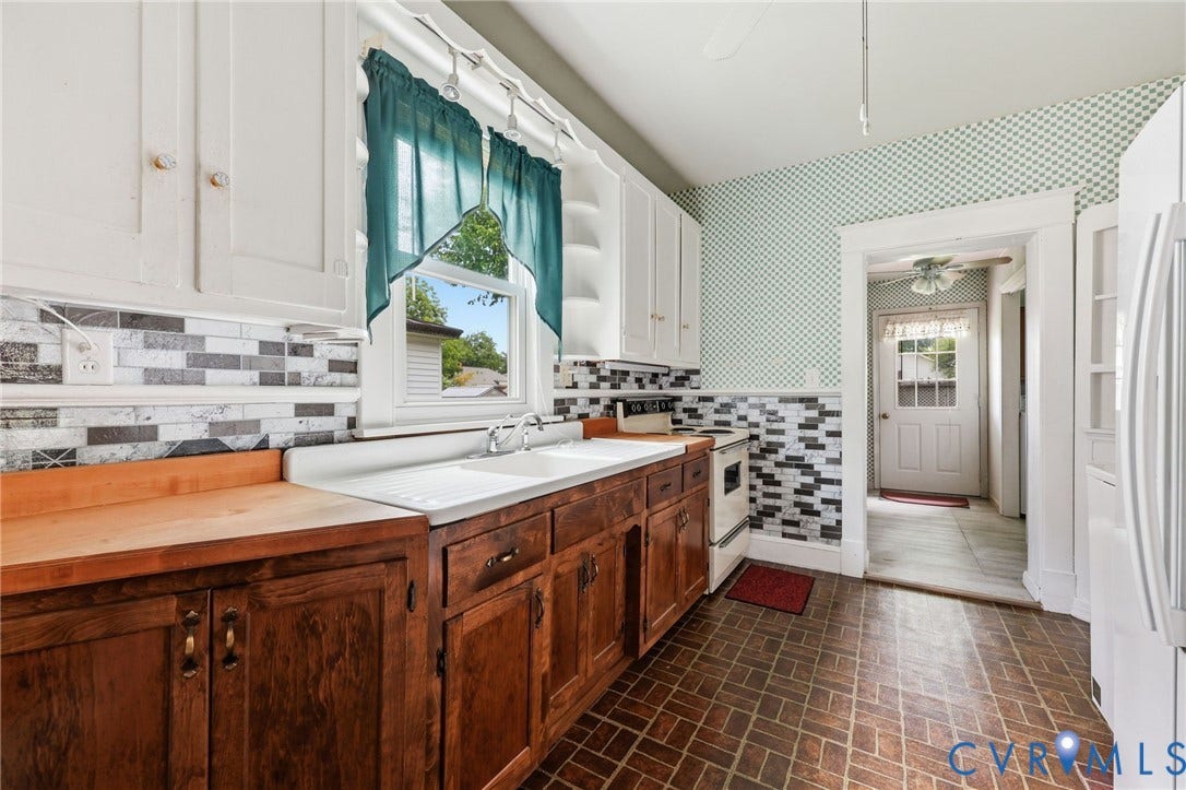 Kitchen featuring wood-finish lower cabinetry, white upper cabinetry, and a mosaic tile backsplash
