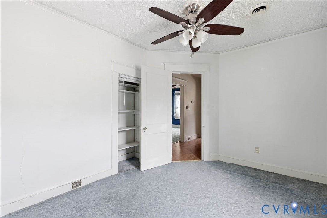 Neutral wall paint, ceiling fan with integrated lighting, built-in closet shelving, and light-toned carpeting