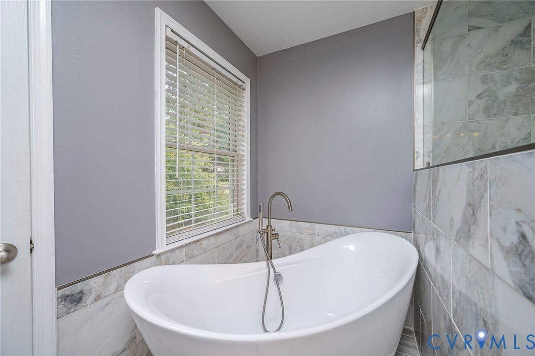 11821 Park Forest Way, Glen Allen, VA 23059 Freestanding soaking tub with a brushed nickel floor-mounted faucet, set against a backdrop of light grey walls and large format marble-look tile