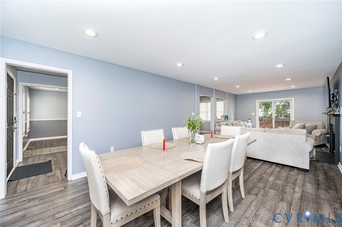 11821 Park Forest Way, Glen Allen, VA 23059 Open-concept dining and living area featuring wood-finish flooring, recessed lighting, light blue walls, a fireplace with a dark mantel, and glass sliding doors