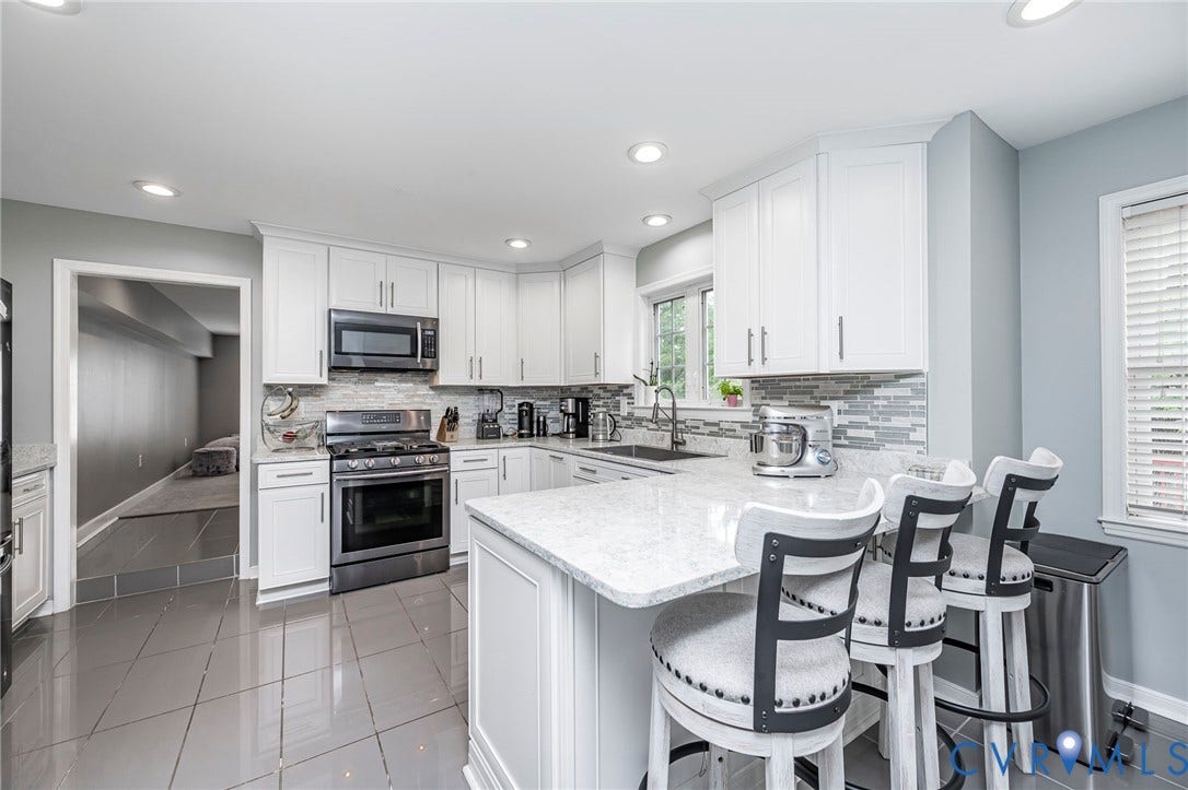 11821 Park Forest Way, Glen Allen, VA 23059 Modern kitchen featuring white cabinetry, stainless steel appliances, a center island with seating, a mosaic tile backsplash, and recessed lighting