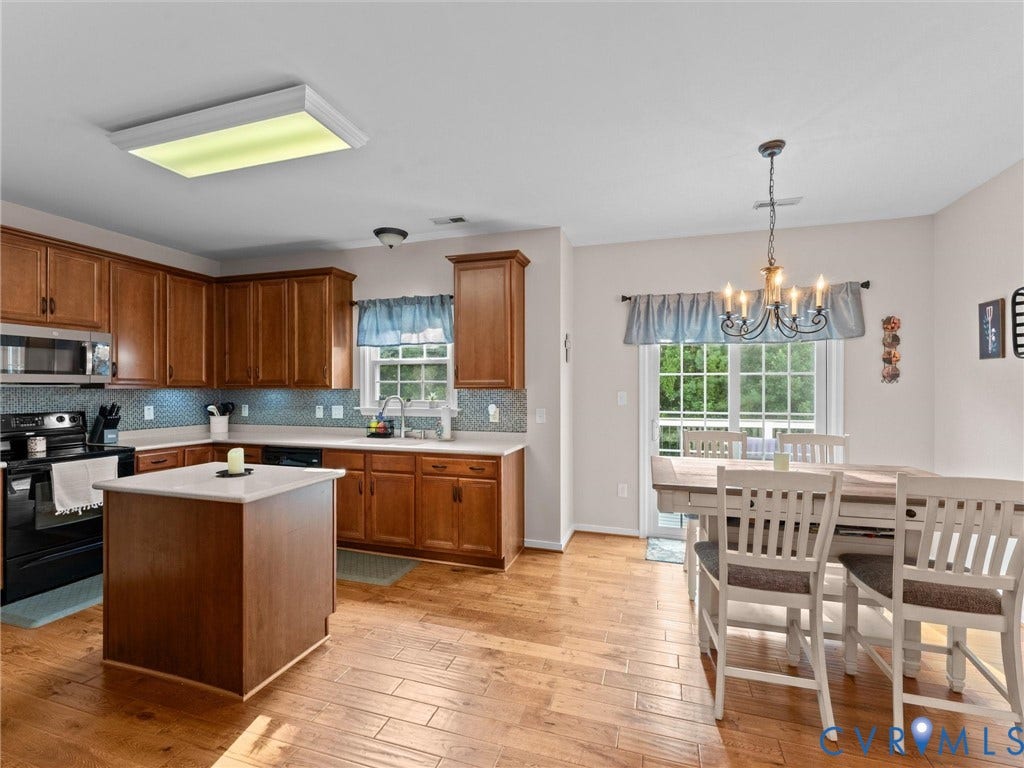 2606 Water Race Terrace, Watermill, Midlothian, VA 23112 Kitchen featuring wood-finish flooring, warm-toned cabinetry, light-toned countertops, a full mosaic tile backsplash, and a central island