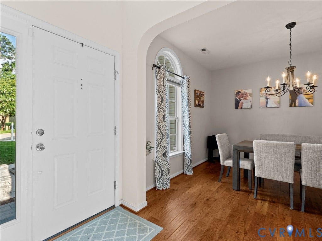 2606 Water Race Terrace, Watermill, Midlothian, VA 23112 Entryway featuring a white paneled door with sidelight, wood-finish flooring, an arched doorway, and a dining area with a chandelier