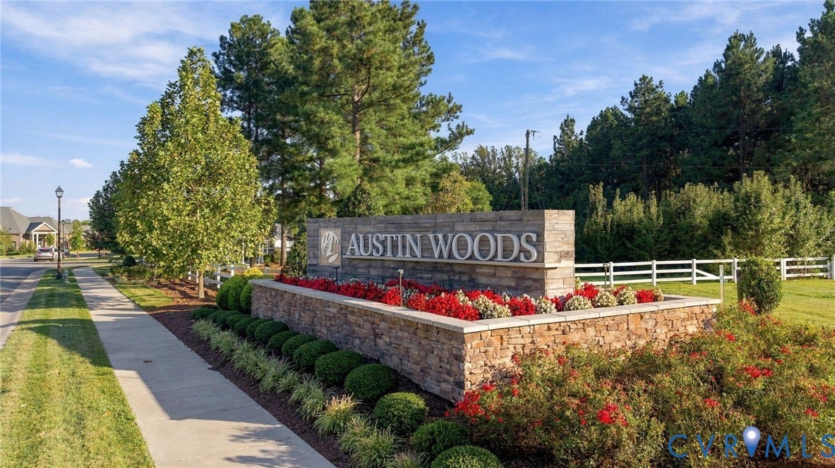 5853 Austin Woods Drive, Chesterfield, VA 23234 Stone-clad community entrance sign featuring "Austin Woods" lettering, decorative landscaping with red and green plantings, and a sidewalk leading into the community