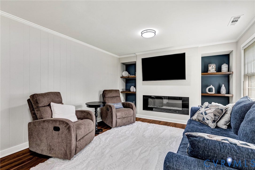 8318 Lydell Drive, Henrico, VA 23228 Wood-finish flooring, recessed built-in shelving with wood accents, and a linear electric fireplace with a white surround