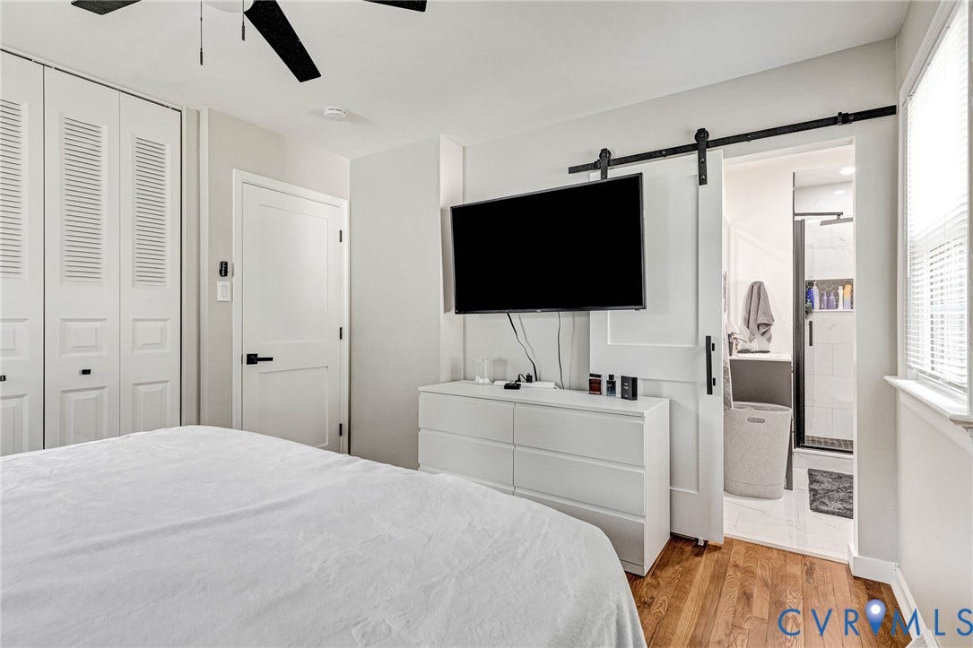 8318 Lydell Drive, Henrico, VA 23228 Hardwood flooring, ceiling fan, white bi-fold closet doors, contemporary paneled door with black hardware, and a barn door leading to an en-suite bathroom