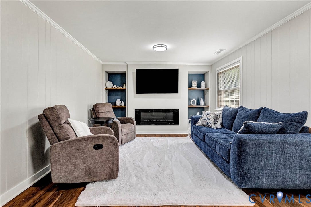 8318 Lydell Drive, Henrico, VA 23228 Wood-finish flooring, white paneled walls, built-in shelving, and an electric fireplace