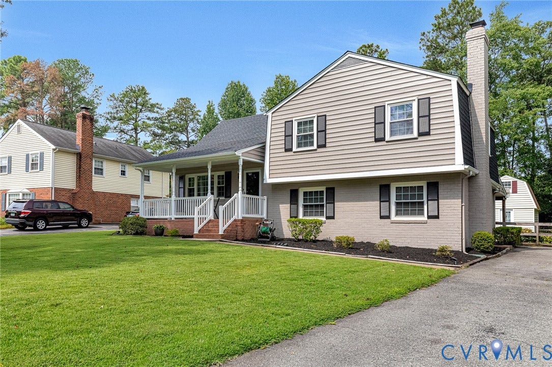8318 Lydell Drive, Henrico, VA 23228 Manicured front lawn, covered porch with white railings, light-colored brick facade, light siding, and prominent chimney feature