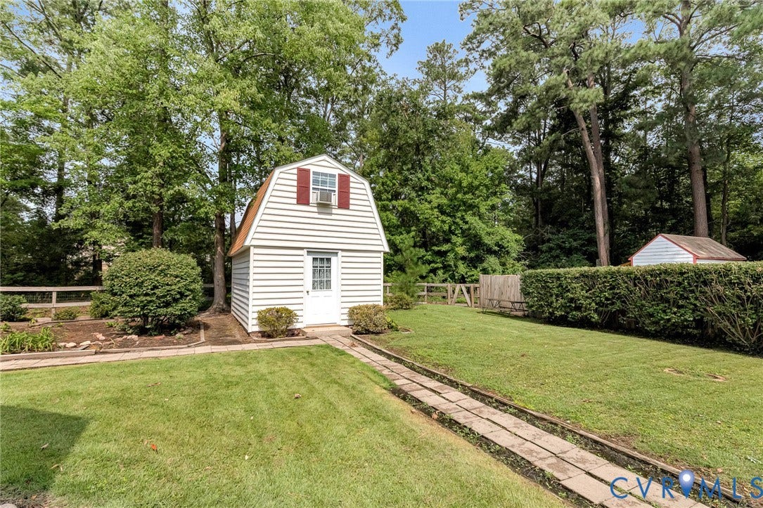 8318 Lydell Drive, Henrico, VA 23228 Detached storage shed with gable roof and window, bordered by mature trees and manicured lawn