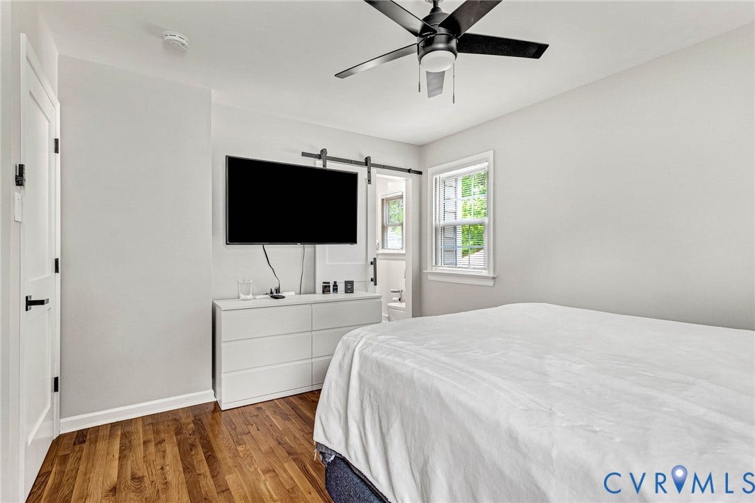 8318 Lydell Drive, Henrico, VA 23228 Hardwood-style flooring, white paneled door with black hardware, barn door-style entry, ceiling fan with light fixture, and window with white trim