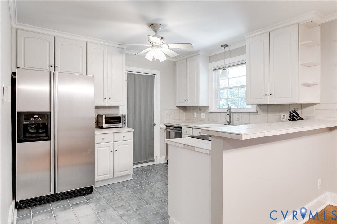 5204 Caledonia Road, Westover Hills, Richmond, VA 23225 White cabinetry, stainless steel side-by-side refrigerator, tile backsplash, tile flooring, and a breakfast bar