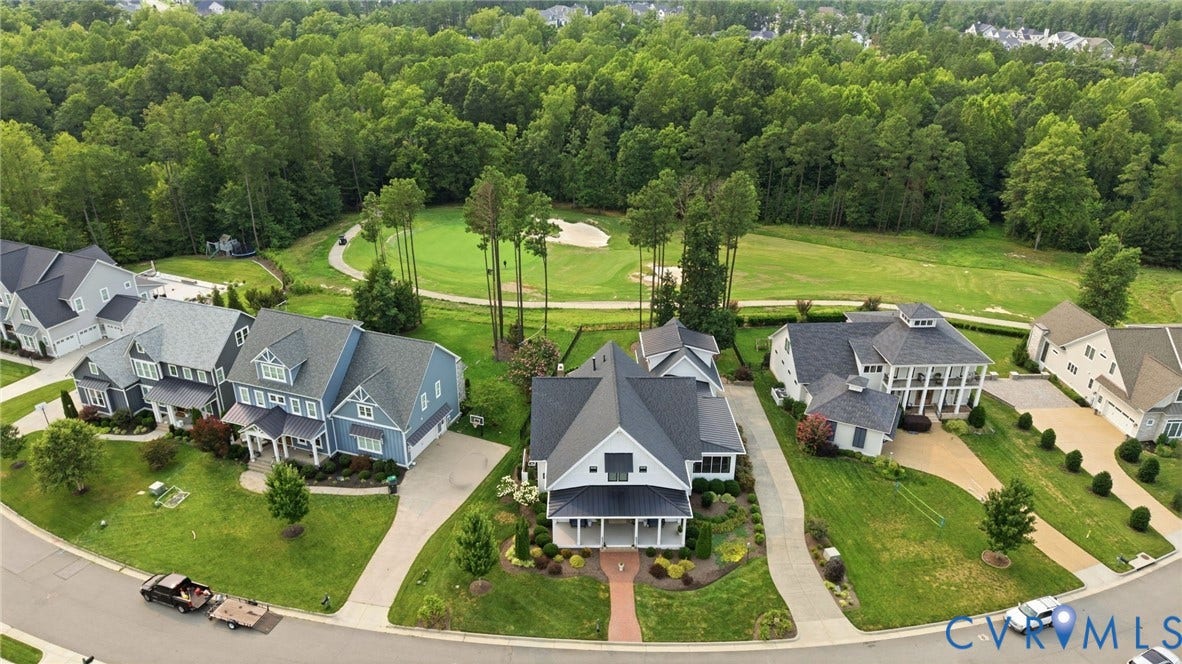 Modern Colonial-style home with a dark gray roof, light siding, and a covered front porch, situated on a cul-de-sac