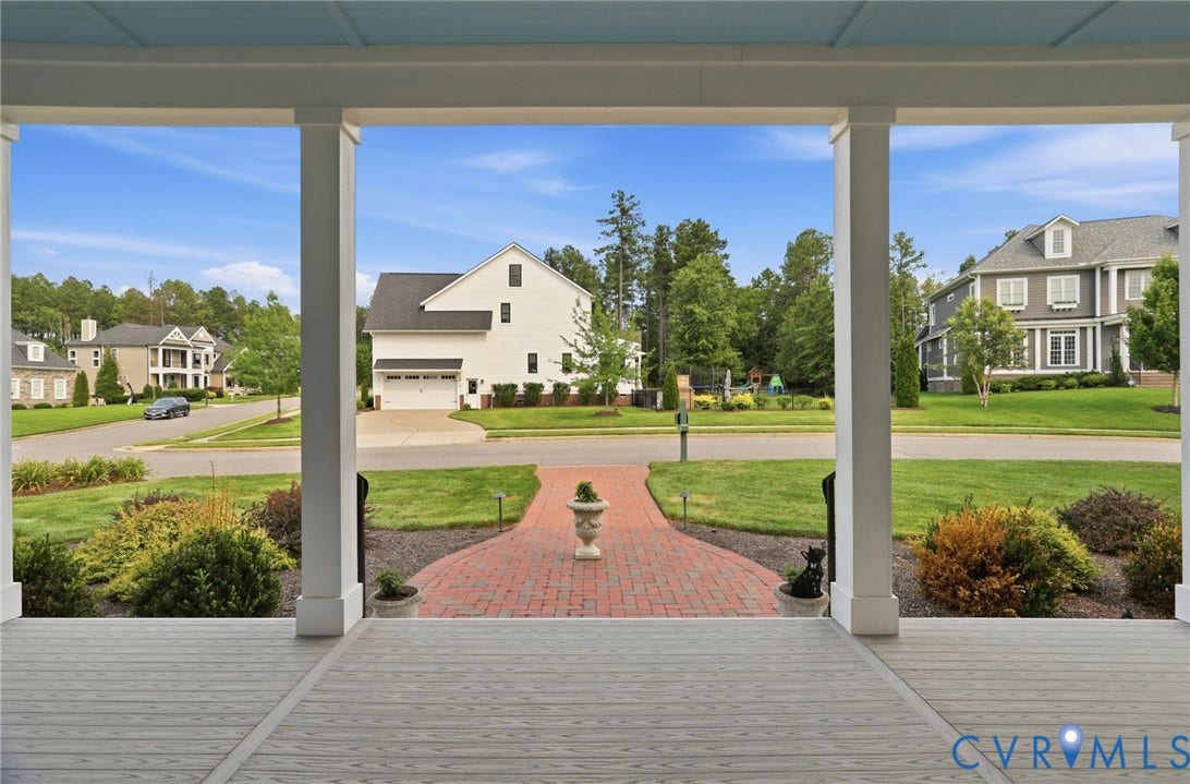 Inviting front porch with a light blue ceiling, white columns, and wood-finish flooring