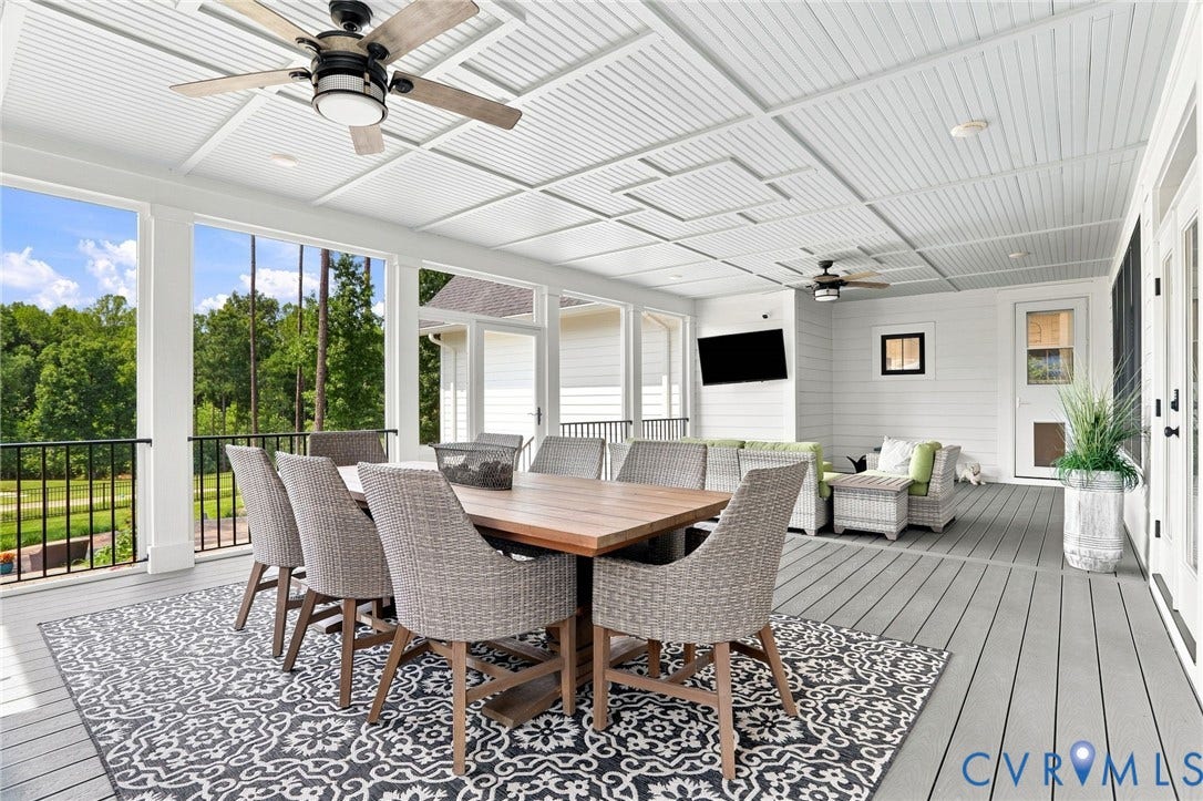 Screened porch featuring a paneled ceiling with dual ceiling fans, composite decking, and a shiplap accent wall