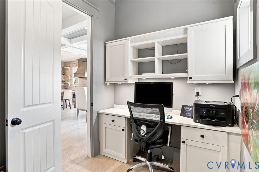 Dedicated office nook featuring built-in white cabinetry, open shelving, and a light-toned countertop