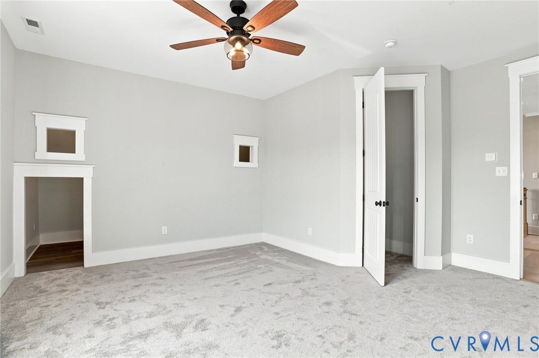 Carpeted room featuring a ceiling fan with wood-finish blades, a built-in architectural niche with wood-finish flooring, two upper wall cutouts, and white trim