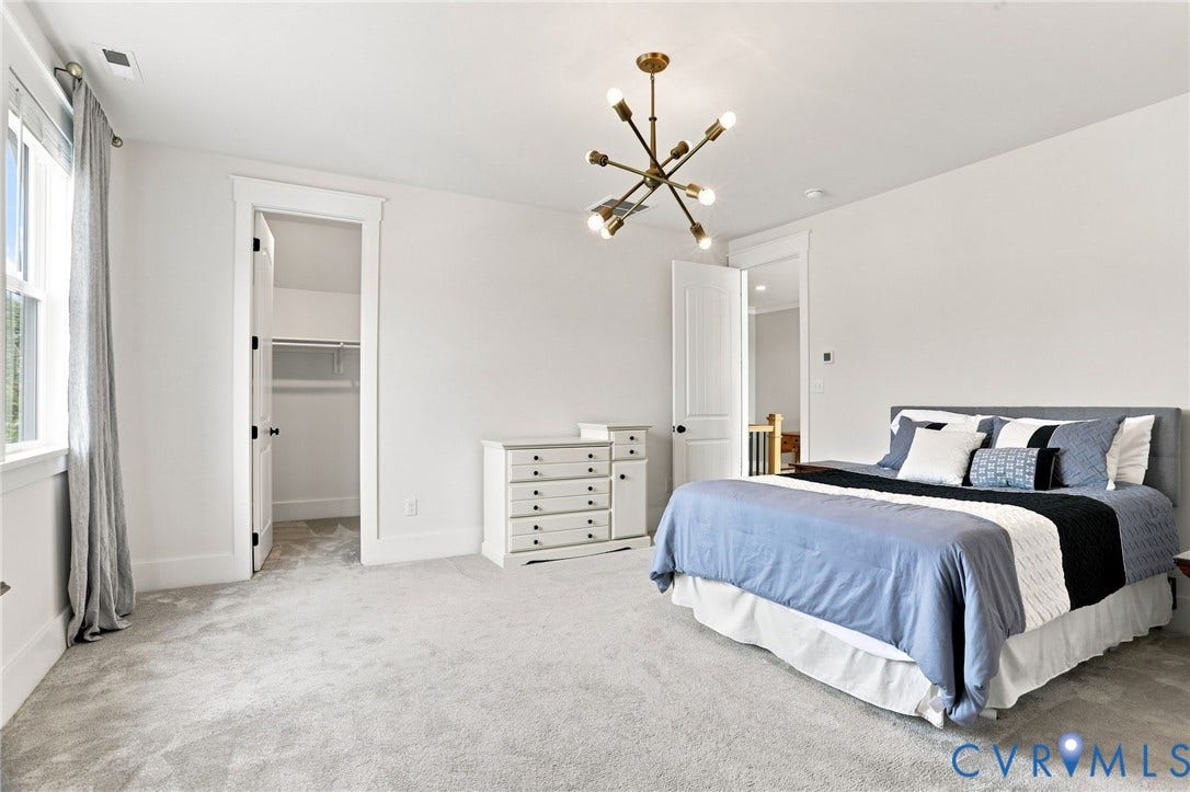 Carpeted room with a modern chandelier and white trim
