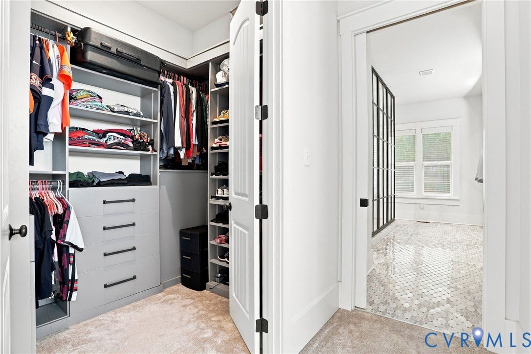 Walk-in closet with custom built-in shelving, hanging rods, and drawers with matte black hardware