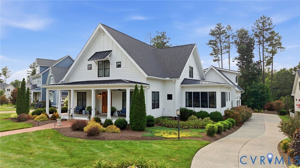 Modern farmhouse exterior featuring white board and batten siding, a dark shingle roof, black window frames, a covered front porch, and a paved driveway