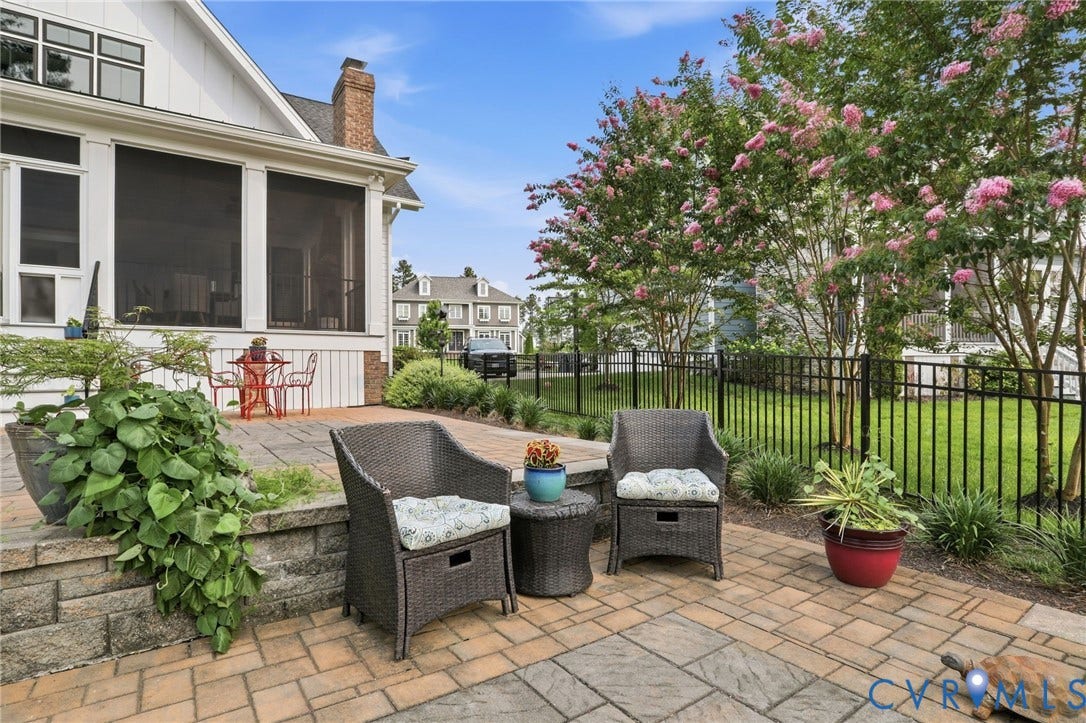 Expansive paver patio featuring a stone retaining wall and a screened-in porch
