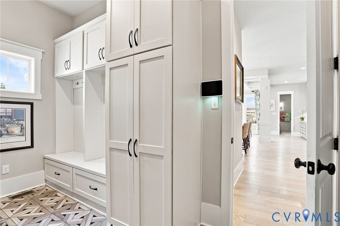Built-in mudroom cabinetry featuring a bench with storage drawers, overhead cupboards, and dedicated hanging space