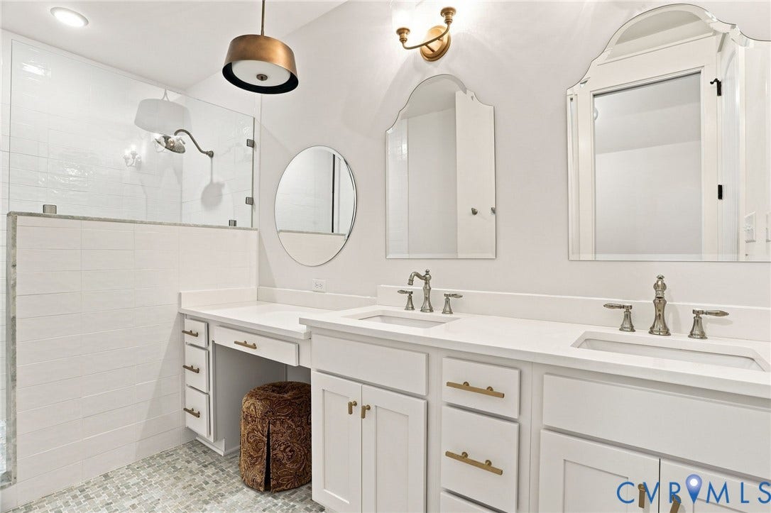 Spacious bathroom featuring a dual vanity with integrated sinks, white cabinetry, and light-toned countertops