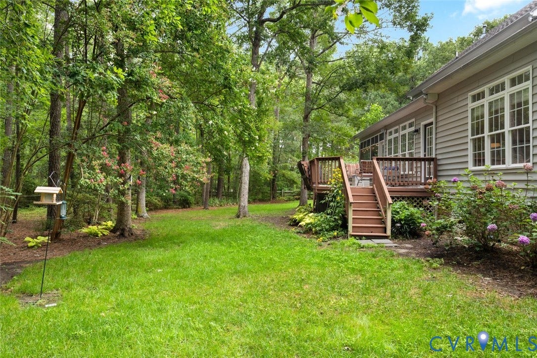 6001 Olde Hartley Place, Glen Allen, VA 23060 Expansive green lawn surrounded by mature trees, featuring a raised wood deck with staircase and multiple windows along the home's exterior