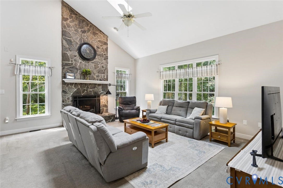6001 Olde Hartley Place, Glen Allen, VA 23060 Vaulted ceiling with a ceiling fan, stone-clad fireplace with a mantel, multiple windows, and light gray wall paint