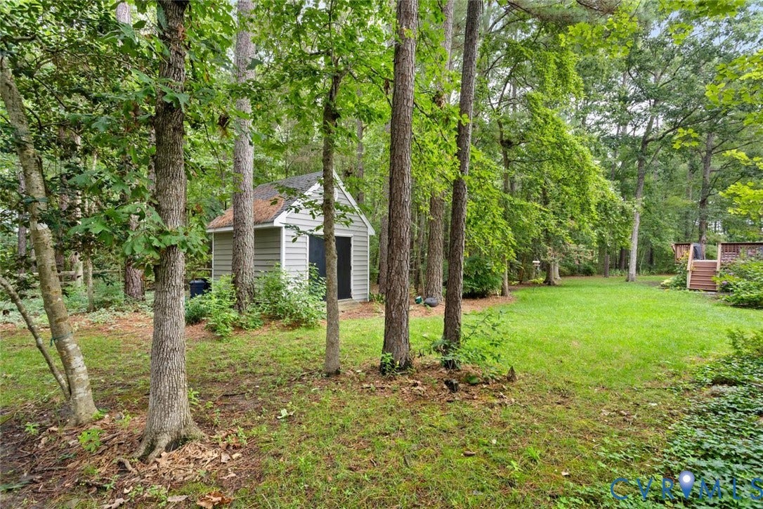 6001 Olde Hartley Place, Glen Allen, VA 23060 Expansive lawn area surrounded by mature trees, featuring a detached storage shed with siding and a shingle roof