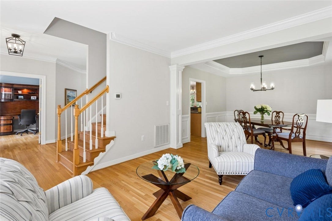 6001 Olde Hartley Place, Glen Allen, VA 23060 Hardwood flooring throughout, a dining area with a tray ceiling and chandelier, a staircase with wood newel posts, an entryway lantern fixture, and crown molding