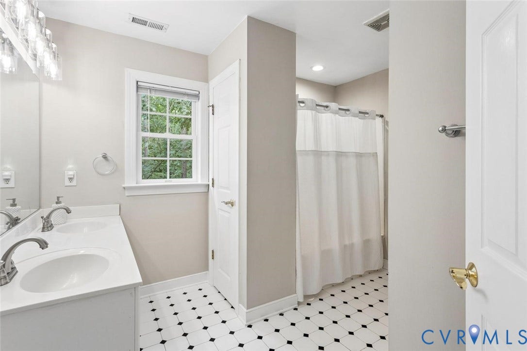 6001 Olde Hartley Place, Glen Allen, VA 23060 Dual sink vanity with white countertop, black and white geometric tile flooring, and a window with natural light
