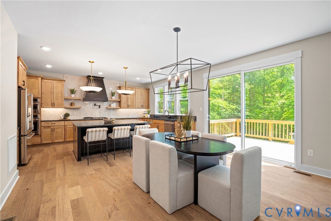 Open-concept kitchen and dining area featuring wood-finish flooring, recessed lighting, and a modern geometric chandelier