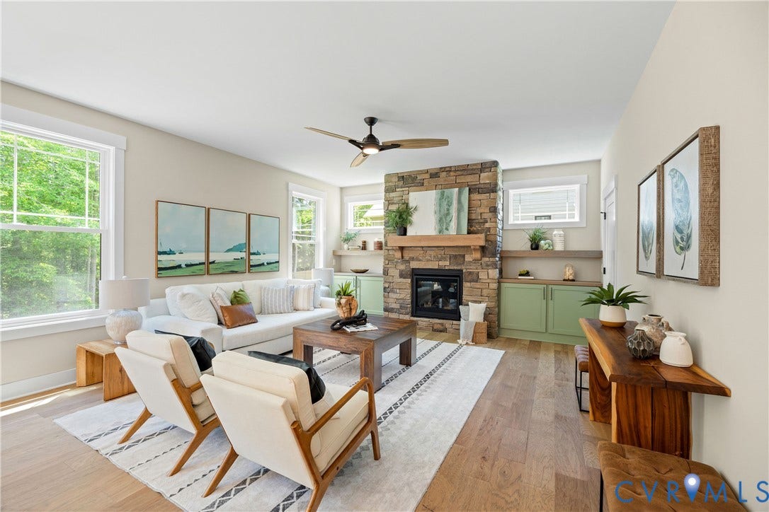 Bright living area featuring wood-finish flooring and a stone-faced fireplace with a natural wood mantel
