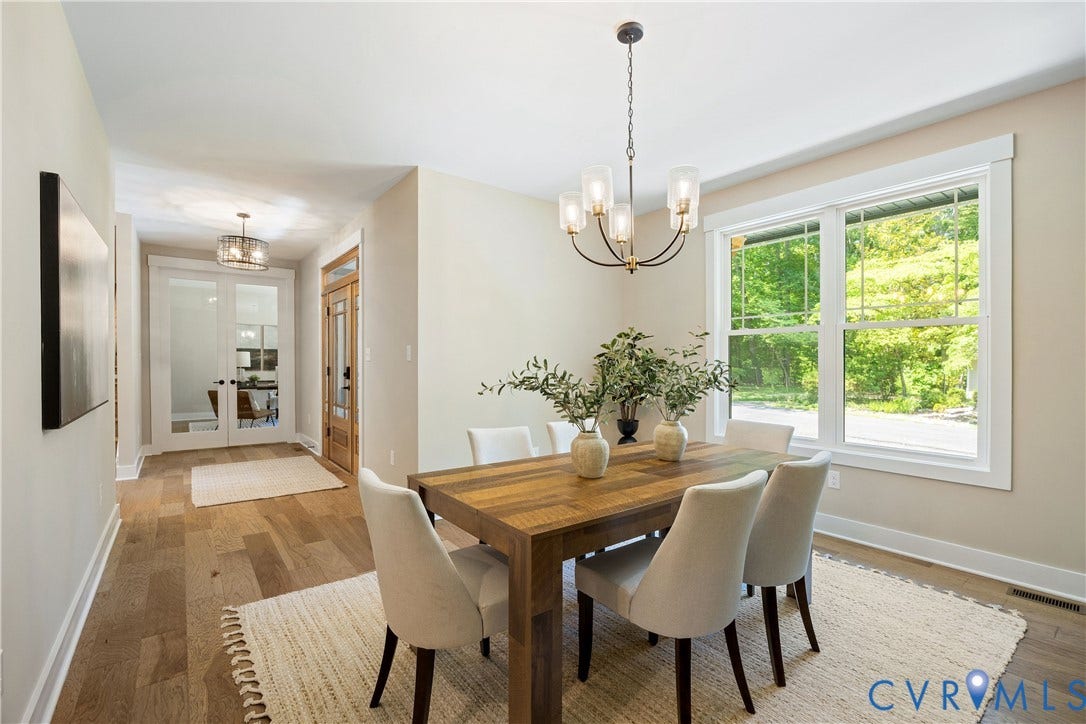 Open-concept dining area featuring wood-finish flooring, a contemporary chandelier, large windows, and a clear sightline into a separate room through glass-paneled double doors