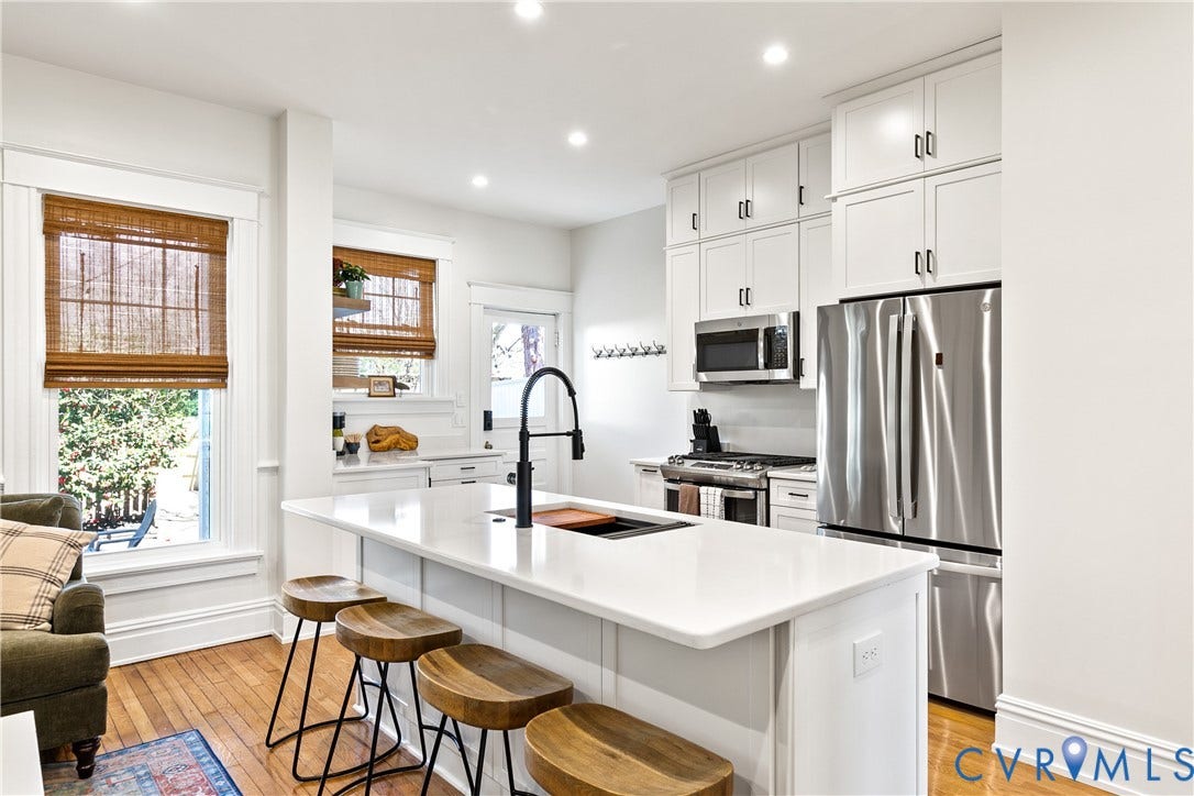 3142 Floyd Avenue, Museum District, Richmond, VA 23221 Kitchen featuring a center island with countertop seating, white cabinetry, stainless steel appliances, and wood-finish flooring