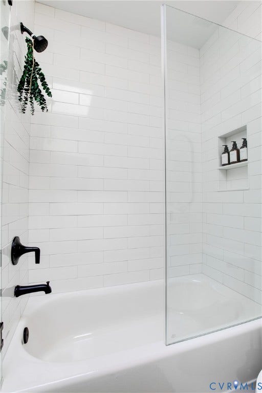 3142 Floyd Avenue, Museum District, Richmond, VA 23221 Bathtub and shower combination featuring white subway tile surround, matte black fixtures, a built-in shower niche, and a clear glass shower screen