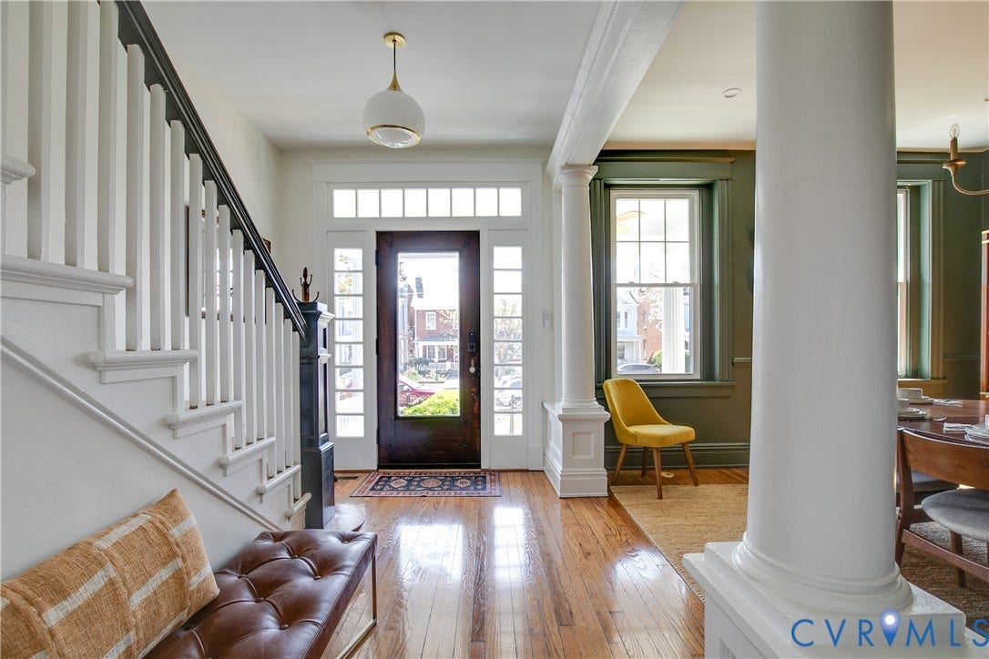 3142 Floyd Avenue, Museum District, Richmond, VA 23221 Front entry featuring a dark wood door with sidelights and transom windows, hardwood flooring, a white spindle staircase with dark wood handrail, and architectural columns