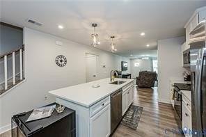 7225 Lyon Taylor Lane, The Groves At New Kent, New Kent, VA 23124 Open-concept kitchen featuring a spacious island with a built-in sink, stainless steel appliances, white cabinetry, and wood-finish flooring