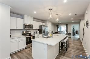 7225 Lyon Taylor Lane, The Groves At New Kent, New Kent, VA 23124 Modern kitchen featuring white cabinetry, stainless steel appliances, a white subway tile backsplash, and a large island with an undermount sink