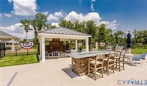 7225 Lyon Taylor Lane, The Groves At New Kent, New Kent, VA 23124 Expansive outdoor amenity space featuring a covered pavilion with a stone fireplace, a large outdoor bar with bar seating, multiple grill stations, and a paved patio area