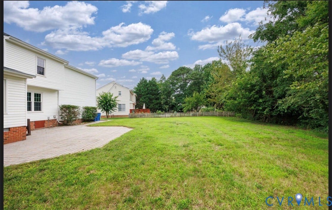 2912 Appleford Drive, Longmeadow, Chester, VA 23831 Expansive green lawn with mature perimeter trees, offering a paver patio and the exterior of a white siding residence with brick foundation accents