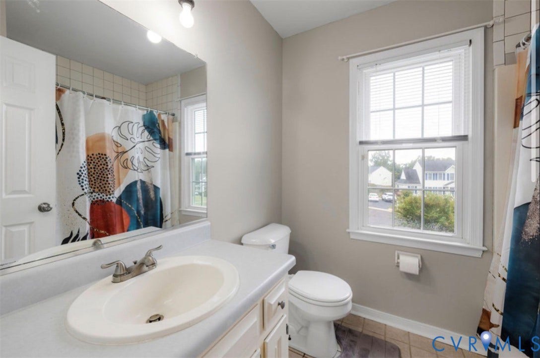 2912 Appleford Drive, Longmeadow, Chester, VA 23831 Vanity with an integrated sink and brushed nickel faucet, large wall mirror, window with blinds, and tiled flooring