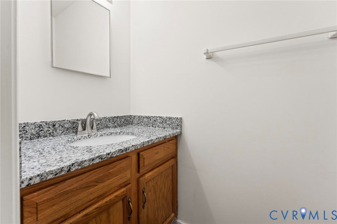 10111 Robin Lee Lane, Henrico, VA 23060 Bathroom vanity featuring warm wood-finish cabinetry, speckled stone countertop, and chrome hardware