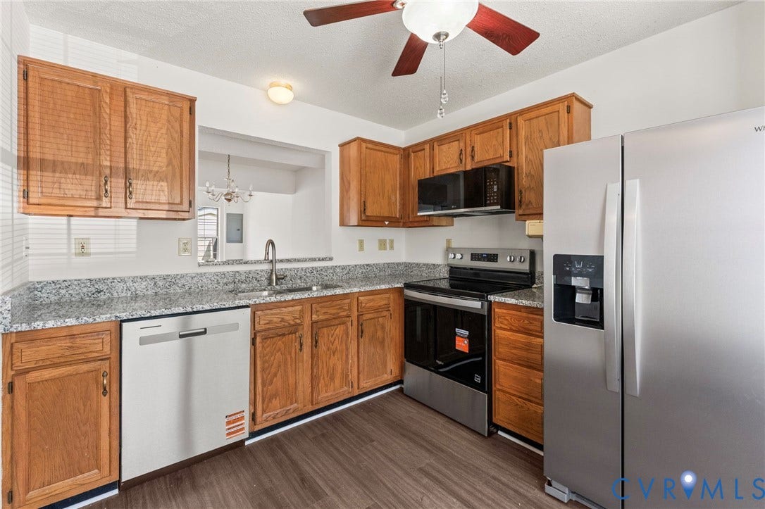 10111 Robin Lee Lane, Henrico, VA 23060 Updated kitchen featuring wood-finish cabinetry, stainless steel appliances including a gas range and refrigerator, granite-style countertops, white subway tile backsplash, a white dishwasher, and wood-finish flooring throughout the space